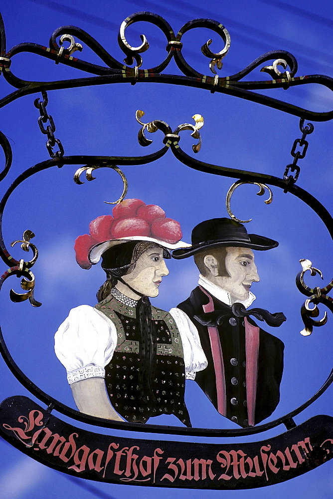 Wrought-iron sign at an inn, couple wearing traditional Black Forest costumes, Baden-Wuerttemberg, Germany, Europe