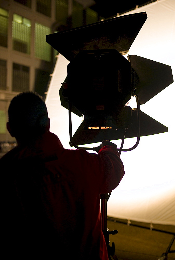 Lighting technician setting up a floodlight on a film set in Germany, Europe