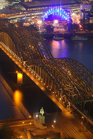 Illuminated city center with Hohenzollern bridge, central train station and "Rock Me" tent, Cologne, NRW, Germany