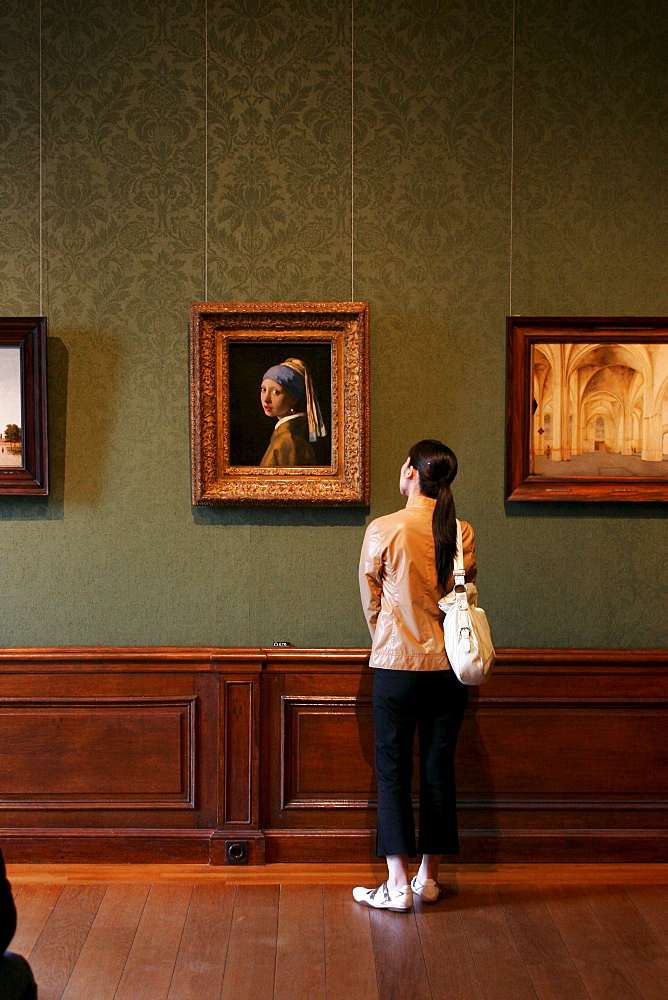 Girl watching the famous painting "Girl with a Pearl Earring " by Dutch painter Johannes Vermeer in the museum Mauritshuis in The Hague Netherlands