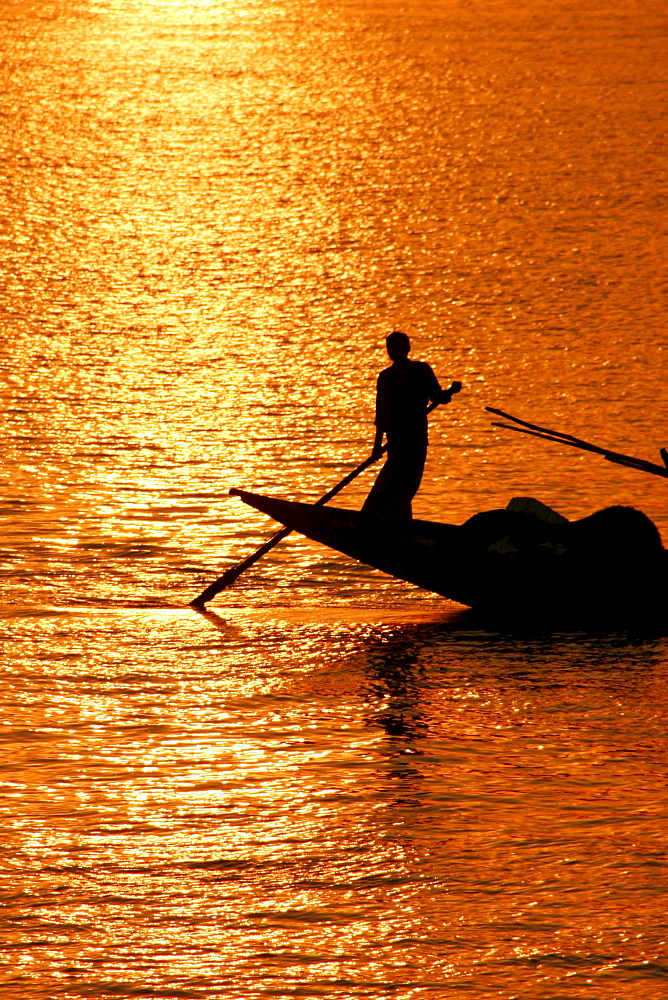 Boatman silhouetted in the evening sun, Hooghly River, Kolkata (Calcutta), West Bengal, India, South Asia