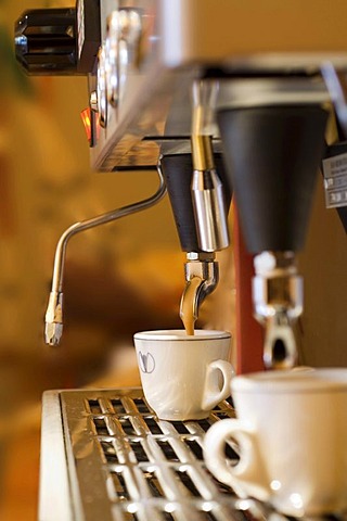 A cup of coffee is prepared with an espresso machine