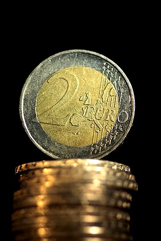 Two Euro coin is standing up to a pile of Euro coins