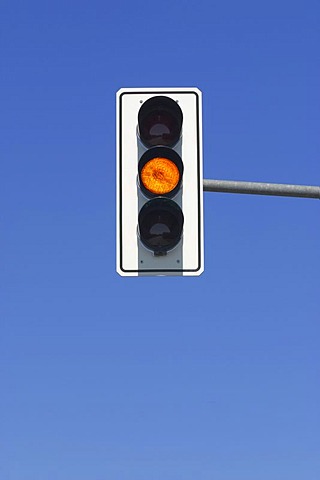 Yellow traffic light in blue sky