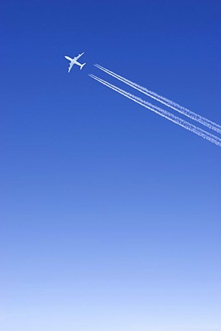 One single passenger jet with condensation trail white in blue sky