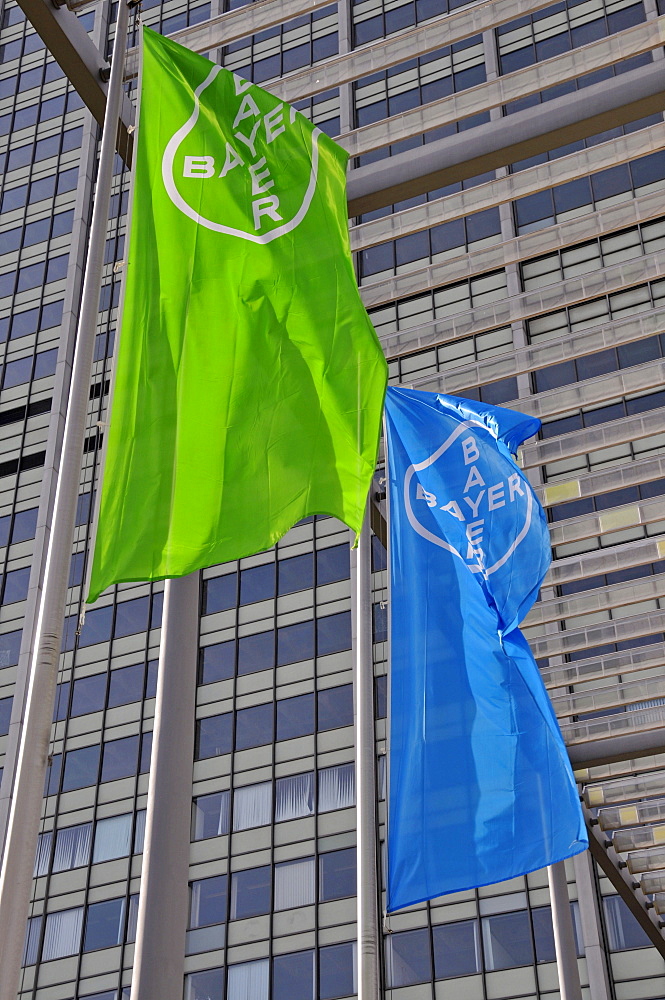 Blue and green flags of the Bayer corporation visible against a high-rise office building at their headquarters in Leverkusen, North Rhine-Westphalia, Germany, Europe