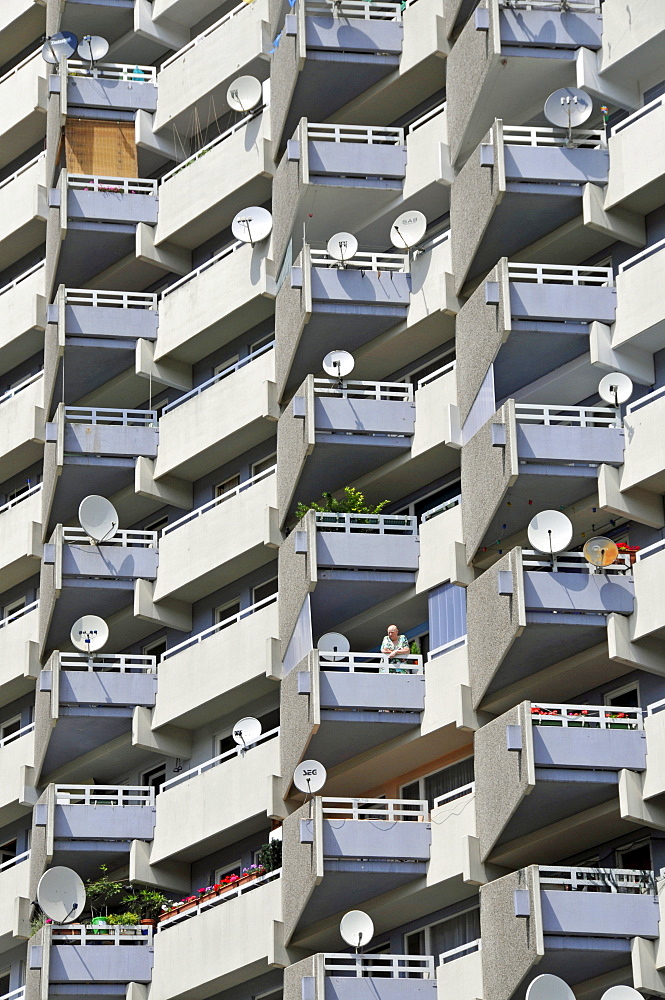 Woman standing in a residential building with balconies and satellite dishes, Chorweiler near Cologne, North Rhine-Westphalia, Germany, Europe