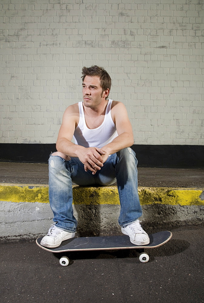 Skateboarder sitting on a loading ramp, relaxed