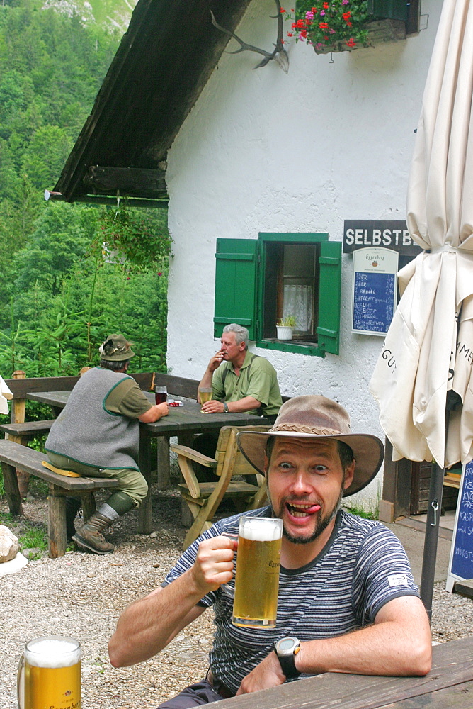 A man enjoys a cool beer at the Mairalp at the base of the mountain Traunstein Upper Austria