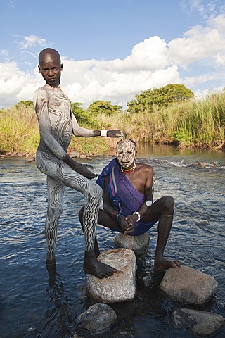 Two Surma men with facial and body paintings in the river, Kibish, Omo River Valley, Ethiopia, Africa