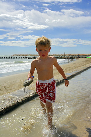 Boy with shovel on the beach, Caorle, Veneto, Italy