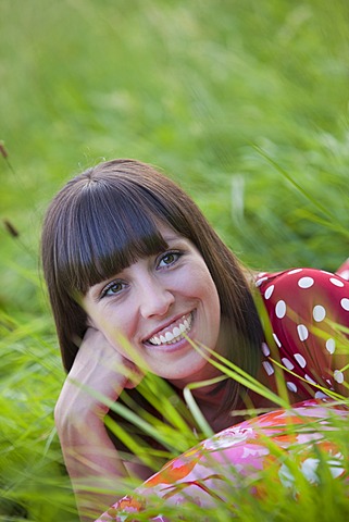 Young woman, 25, lying in a meadow