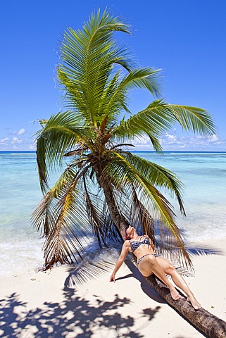 Young woman lying on a coconut tree on the beach, Anse La Passe, Silhouette Island, Seychelles, Africa, Indian Ocean