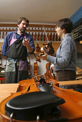 Violin-maker (luthier) with a customer in his shop