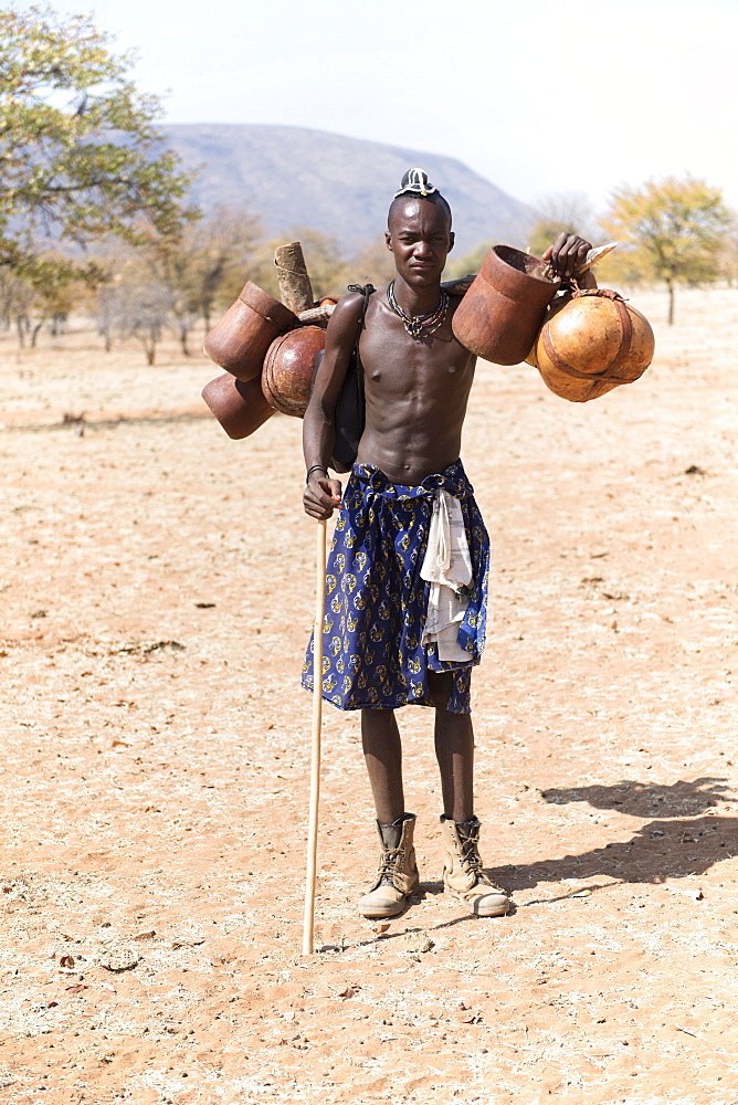 Young Himba man carries food on the cattle drive, Kaokoveld, Namibia, Africa