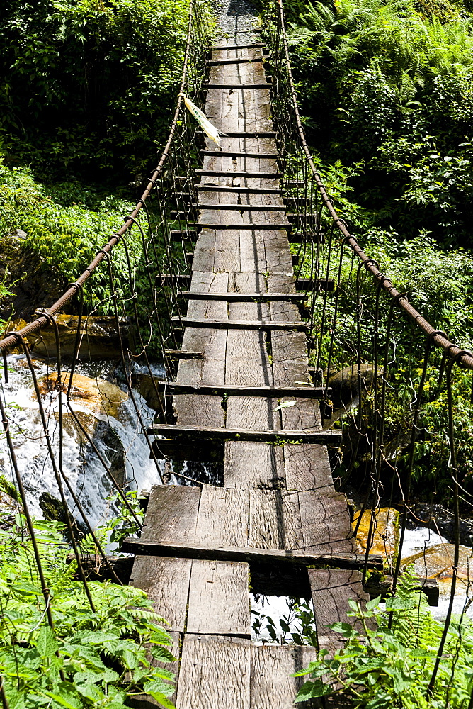 Old wooden suspension bridge across small river in Upper Modi Khola valley, Landruk, Kaski District, Nepal, Asia