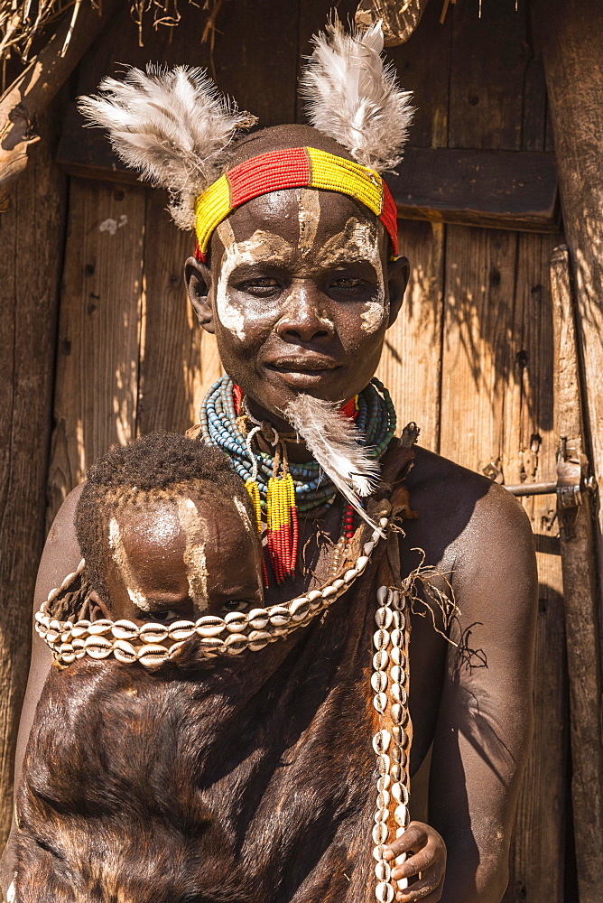 Young woman with toddler in traditional clothes made of goatskin, Karo tribe, Southern Nations Nationalities and Peoples' Region, Ethiopia, Africa