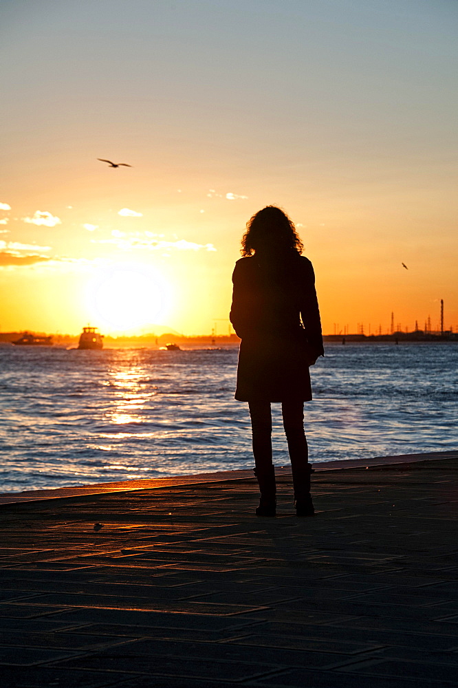 Woman watching the sunset on the Zattere promenade, Venice, Italy, Europe