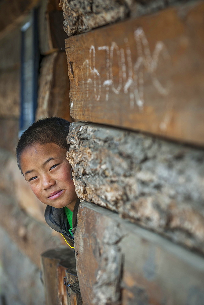 A boy looks out of a house, Wangue, Himalayas, Kingdom of Bhutan