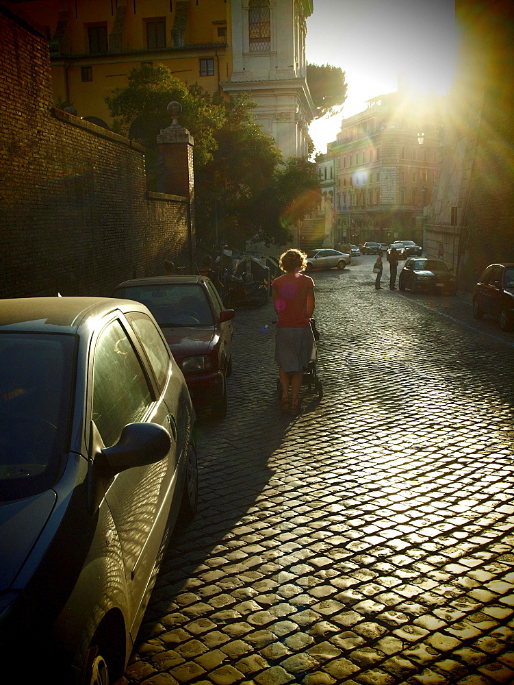 Woman backlit on an old cobblestone street in the evening, Rome, Italy, Europe