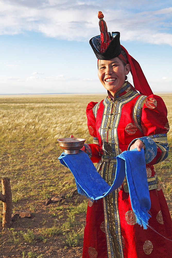 Woman in traditional dress with traditional welcome utensils, blue cloth and bowl of milk, Gobi desert, Sudwuste, Omnogovi Province, Mongolia, Asia