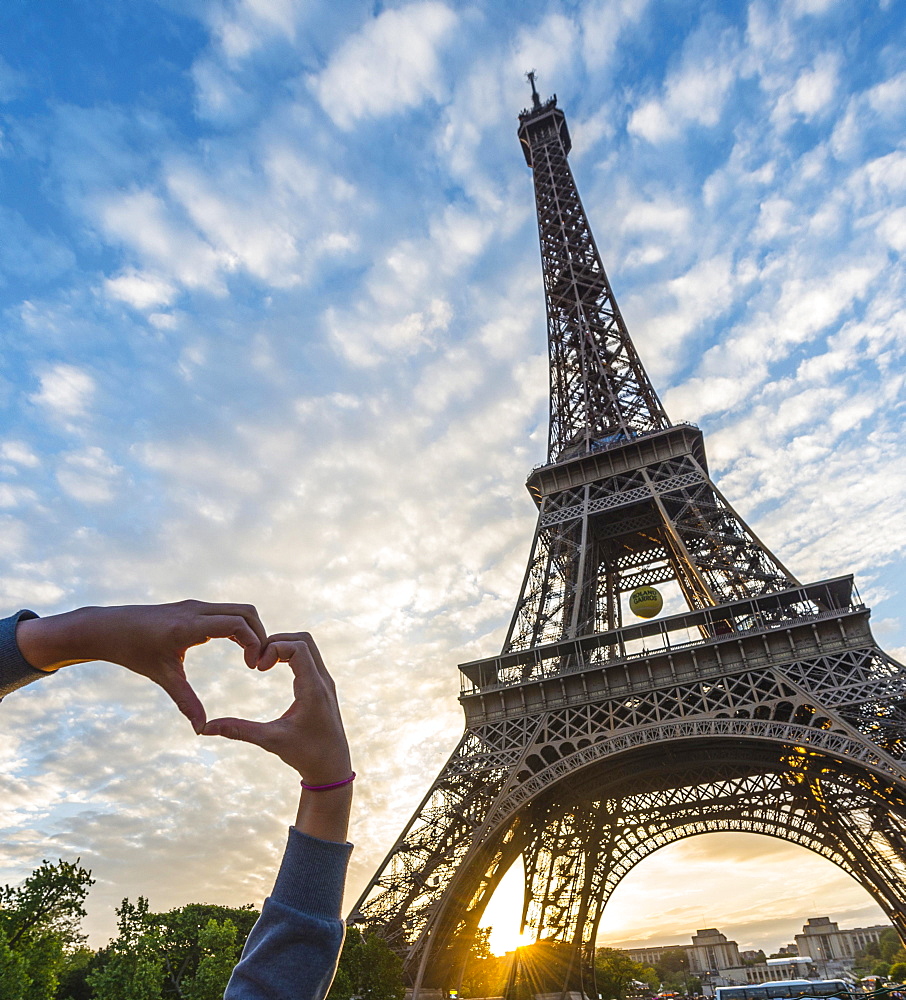 Hands forming heart, sunset behind Eiffel Tower, Champ de Mars, Paris, Ile-de-France, France, Europe