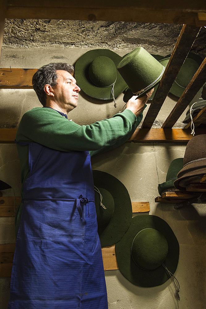 Hatter placing wool felt hat with shaping cord to dry on wooden boards in drying room, hatmaker workshop, Bad Aussee, Styria, Austria, Europe