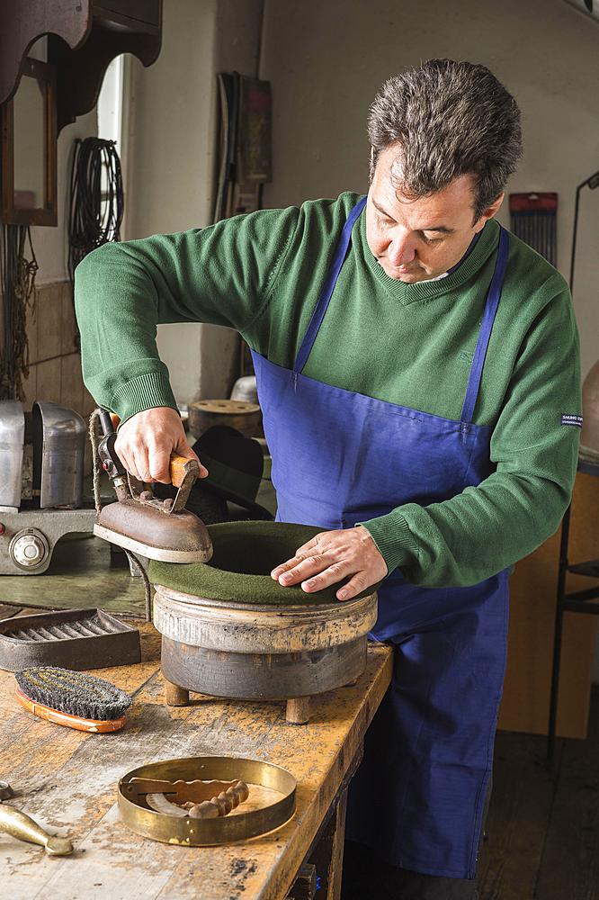 Hatter ironing dry wool felt hat over edge mold, hatmaker workshop, Bad Aussee, Styria, Austria, Europe