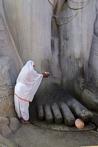 Jain pilgrim is pouring water on the feet of the gigantic statue of Gomateshwara in Sravanabelagola, Karnataka, India, Asia