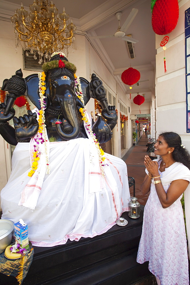 Hindu woman praying to roadside statue, Little India, Singapore, Southeast Asia, Asia