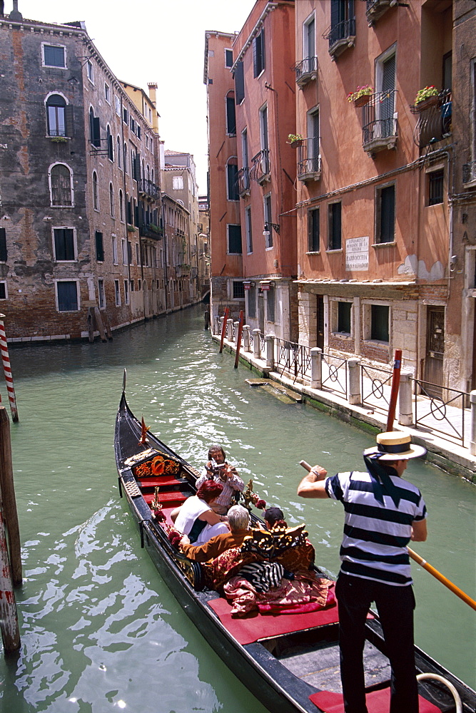 Gondolier with tourists in his gondola on the Grand Canal, Venice, UNESCO World Heritage Site, Veneto, Italy, Europe