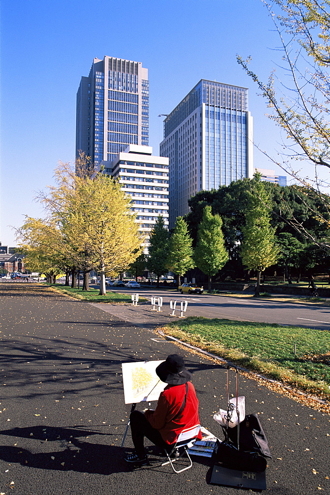 Artist painting autumn leaves and Marunouchi business area skyline, Tokyo, Honshu, Japan, Asia