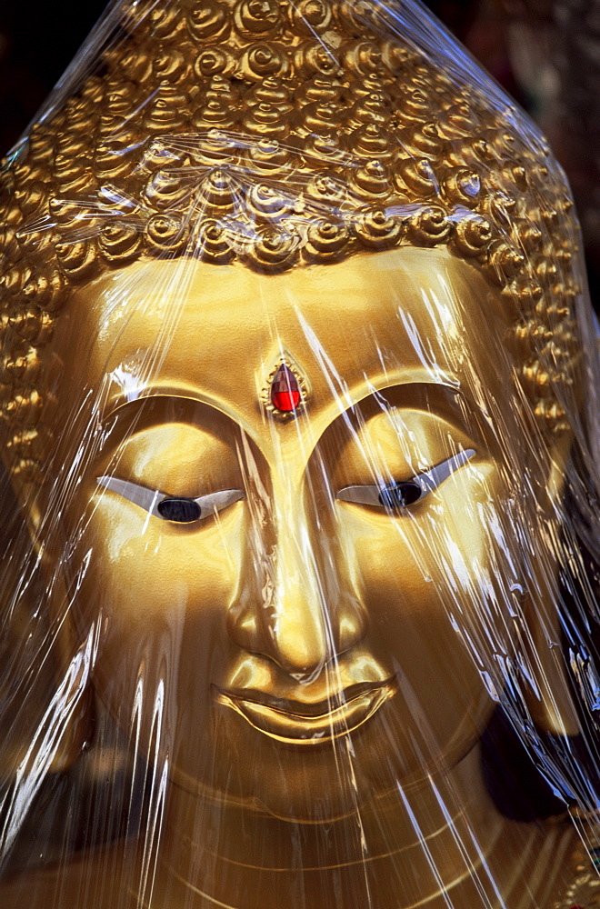 Plastic wrapped Buddha statue head, Thailand, Southeast Asia, Asia