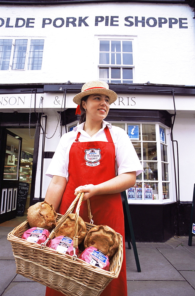 Sales girl holding basket of Melton Mowbray pork pies in front of the Olde Pork Pie Shop, Melton Mowbray, Leicestershire, England, United Kingdom, Europe