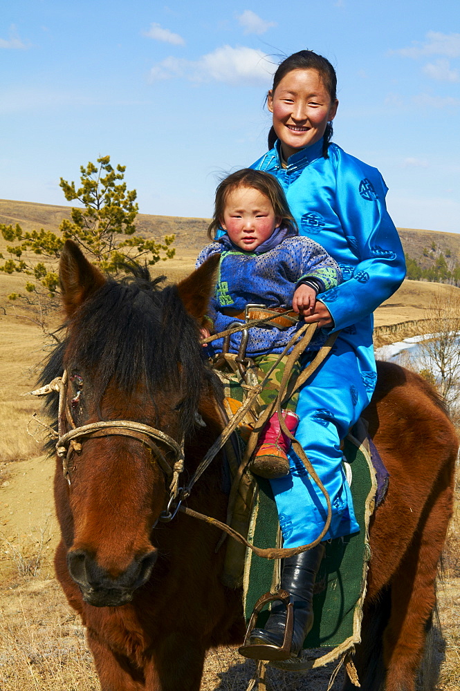 Young Mongolian woman and child in traditional costume (deel) riding a horse, Province of Khovd, Mongolia, Central Asia, Asia