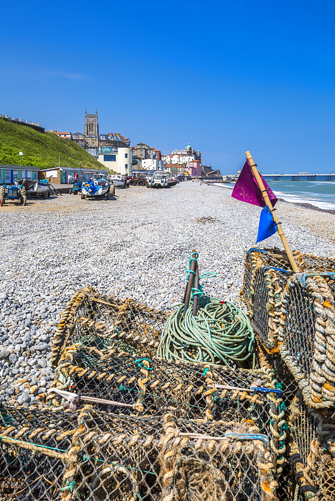 View of fishing baskets on the beach and Parish Church overlooking pier on a summer day, Cromer, Norfolk, England, United Kingdom, Europe