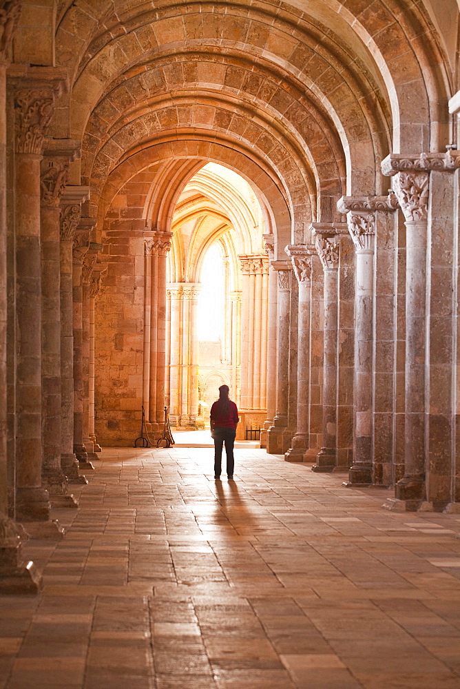 A lady slowly walks down an aisle in the Basilique Sainte-Marie-Madeleine of Vezelay, Yonne, Burgundy, France, Europe