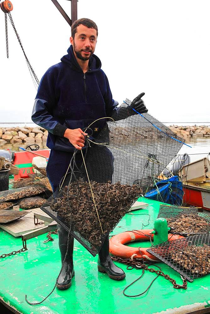 Oysterman carrying a bag of oysters, Etang de Thau, France