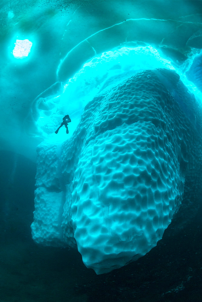 Only in springtime, when the hard winter slowly subsides, are the ice-cold waters suitable for divers who can dive around a iceberg that floats in crystal-clear water, Tasiilaq, East Greenland