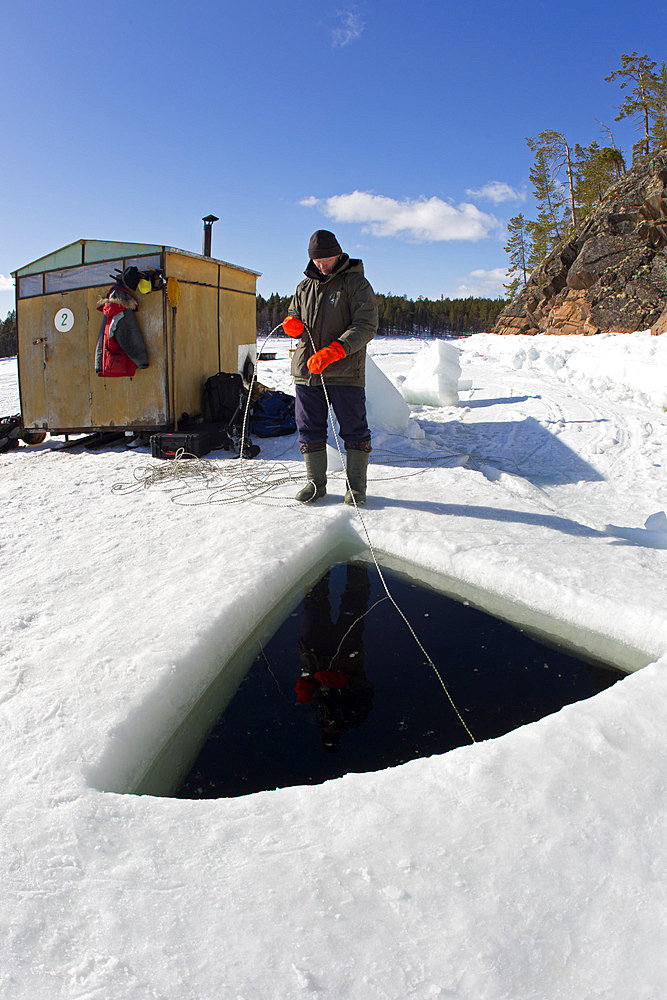 Person who provide contact with the divers inside the maina (sawed entry hole) to dive under the ice, Arctic circle Dive Center, White Sea, Karelia, northern Russia