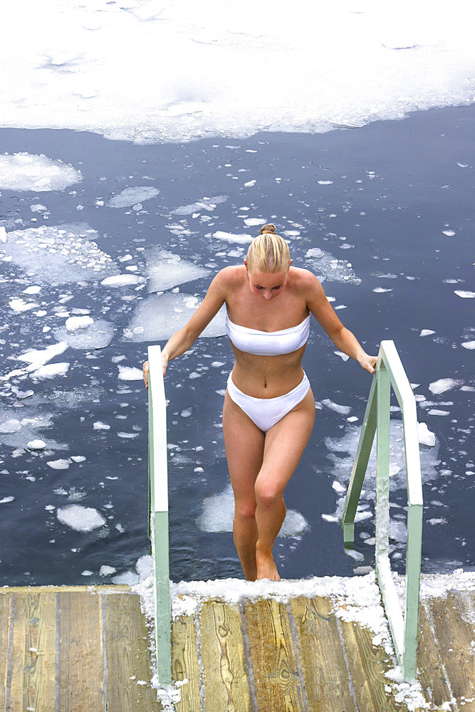 Young woman after a refreshing bath in a fjord before going to a sauna. Nordic bath amid the ice, Oslo, Norway