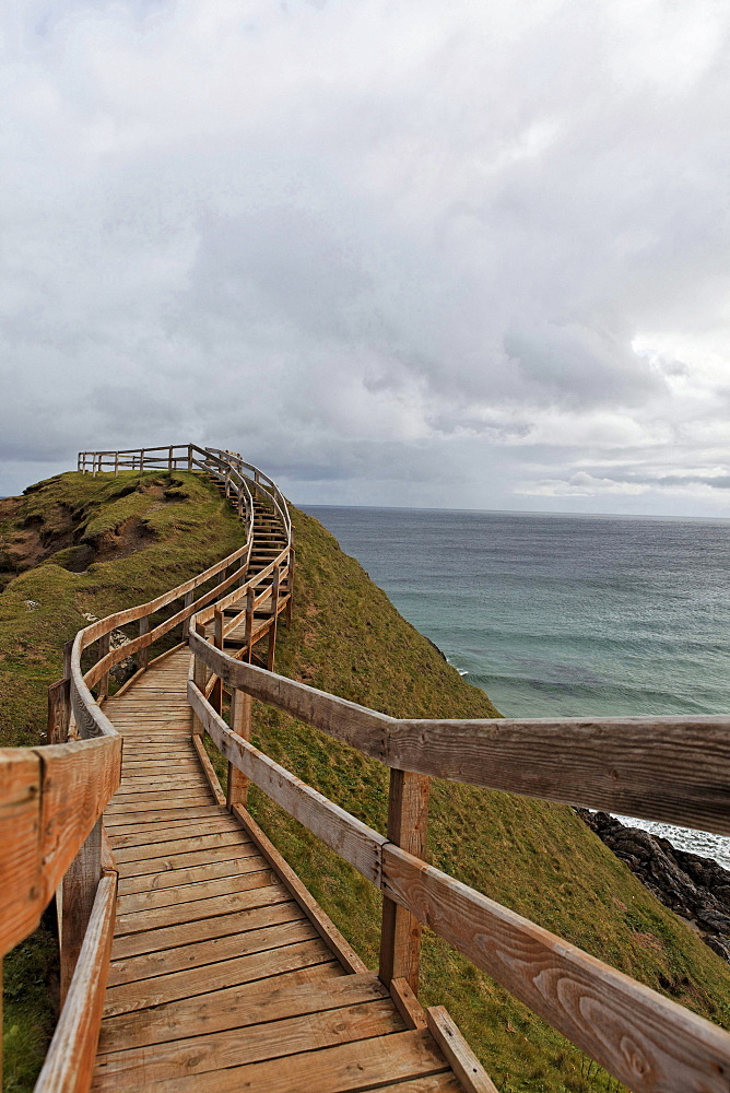 path up on rock beach sea with surf sky with clouds landscape mood