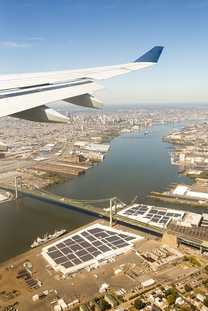 Approaching Philadelphia, over the Benjamic Franklin Bridge on the Delaware River, with harbour front warehouses covered in solar panels. USA.