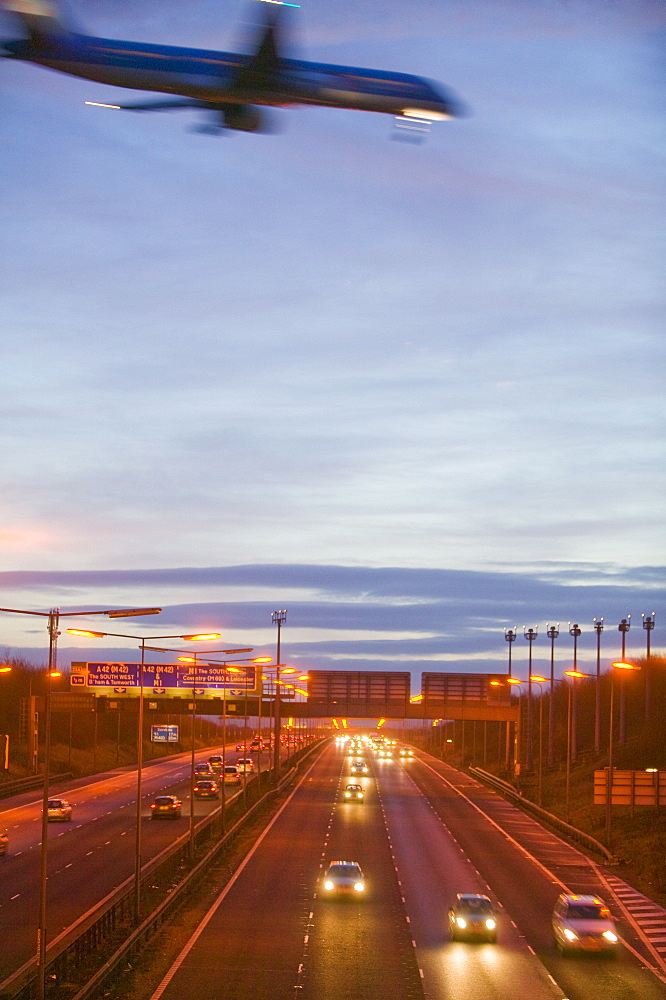 A plane flying over car lights on the M1 motorway in Leicestershire, England, United Kingdom, Europe