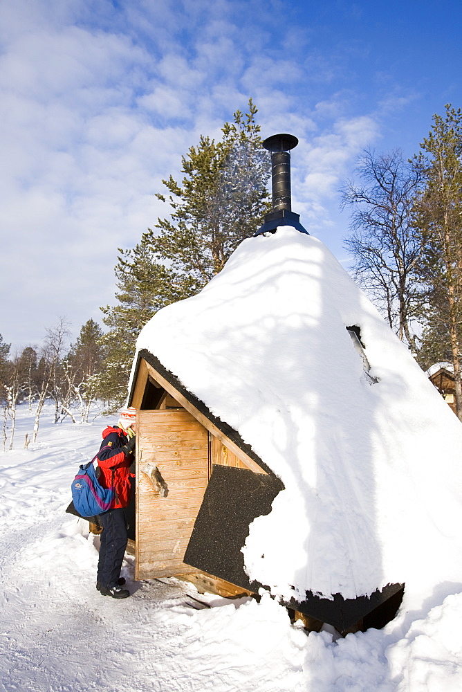 A woman enters a shelter cabin in the Urho Kehkkosen National Park near Saariselka, Northern Finland, Finland, Scandinavia, Europe