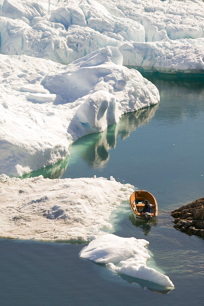 An Inuit fishing boat sails through icebergs from the Jacobshavn glacier (Sermeq Kujalleq), Greenland, Polar Regions