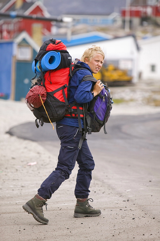 Traveller weighed down with heavy rucksacks in Ilulissat, Greenland, Polar Regions