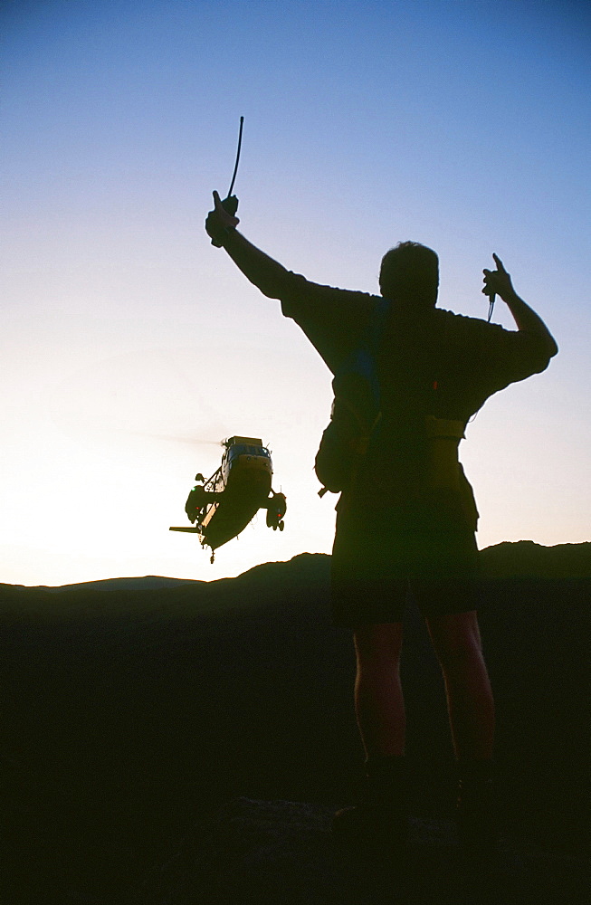 A mountain rescue member attracts an approaching Sea King helicopter to the casualty site on Fairfield in the Lake District, Cumbria, England, United Kingdom, Europe