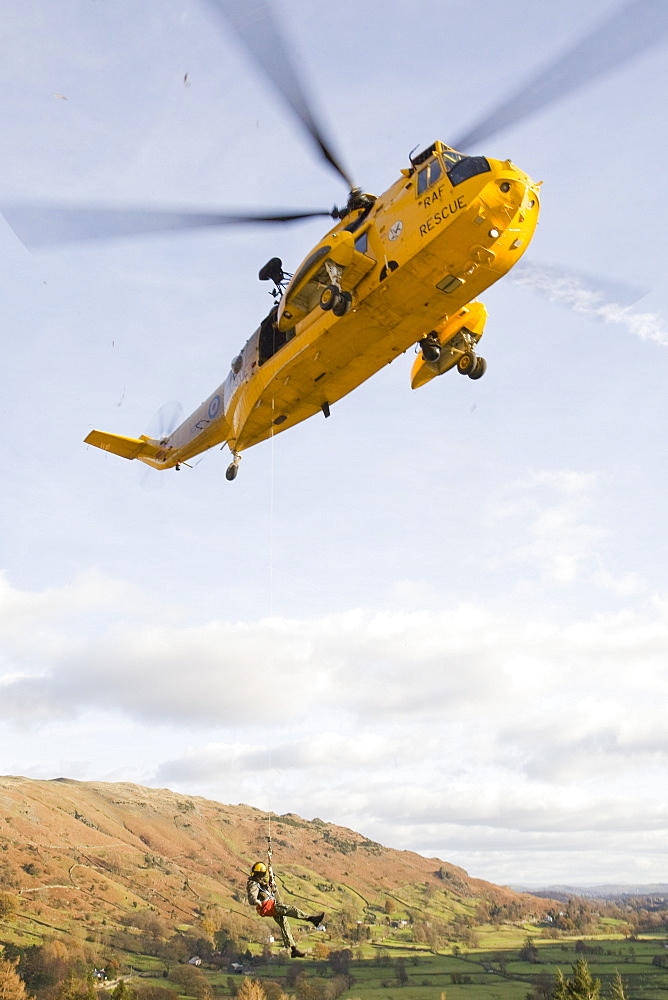 An RAF Sea King helicopter evacuates a seriuosly injured climber with a broken femur from a mountain rescue site in the Langdale Valley, Lake District, England, United Kingdom, Europe