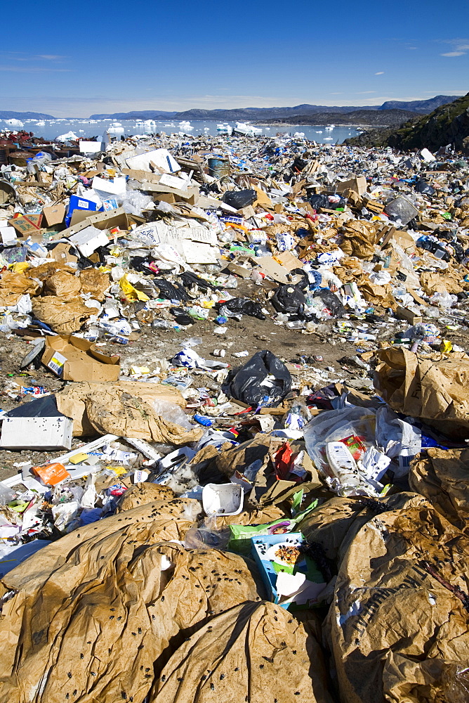 Rubbish dumped on the tundra outside Ilulissat in Greenland with icebergs behind from the Sermeq Kujalleq (Ilulissat Ice fjord), a UNESCO World Heritage Site, Greenland, Polar Regions